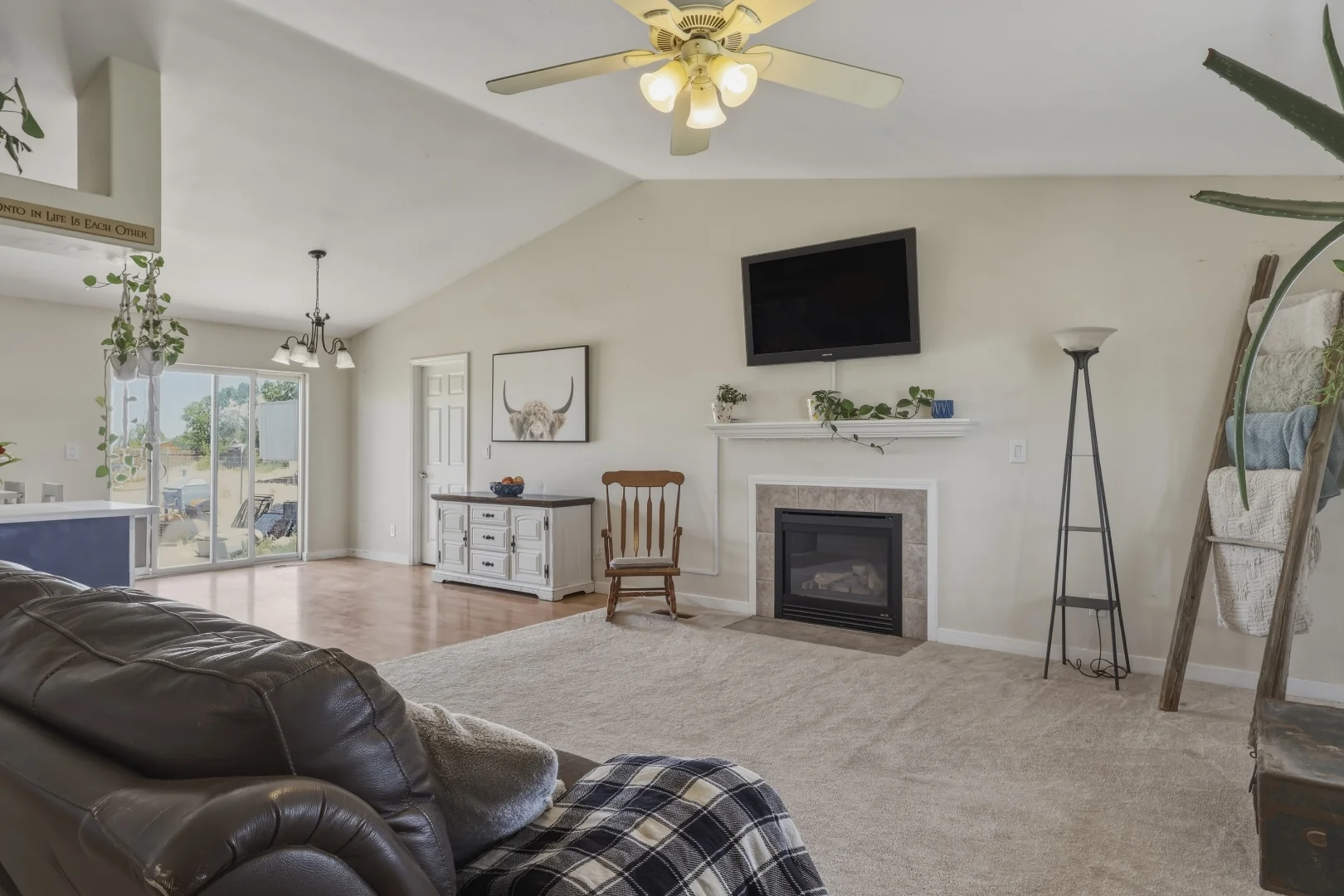 Living area with tile-surround gas fireplace, ceiling fan, and vaulted ceiling
