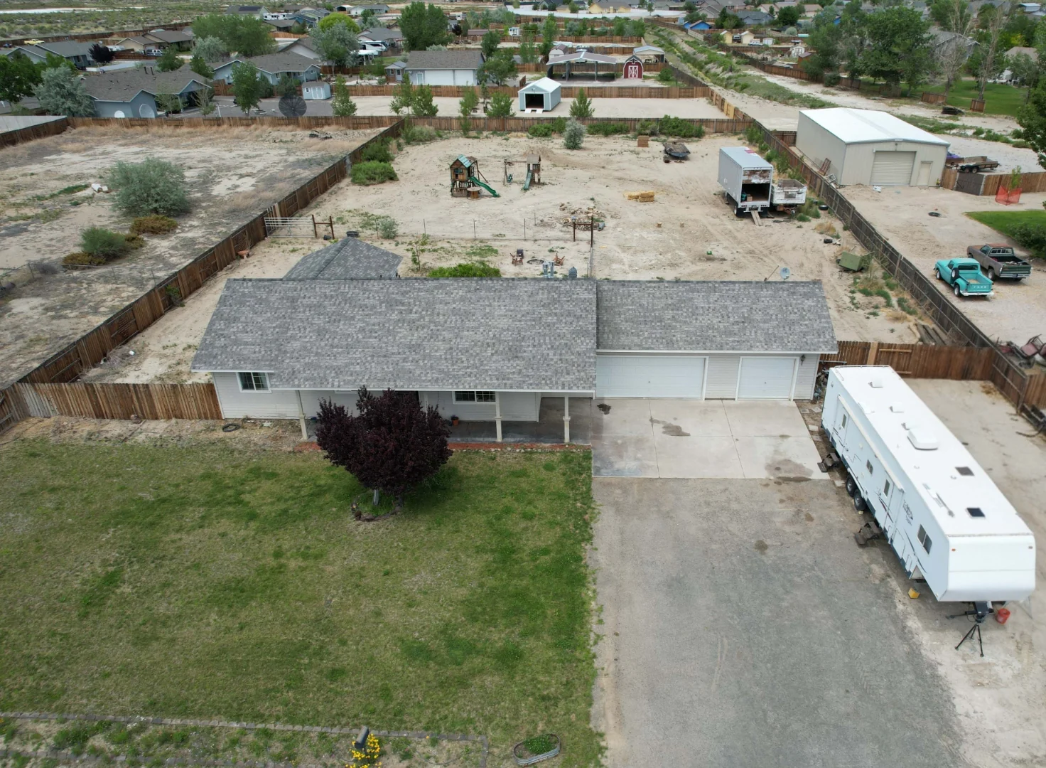 Aerial drone shot showing the full 1-acre lot and front of the property